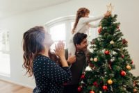 Father with daughter on his back while decorating a tree